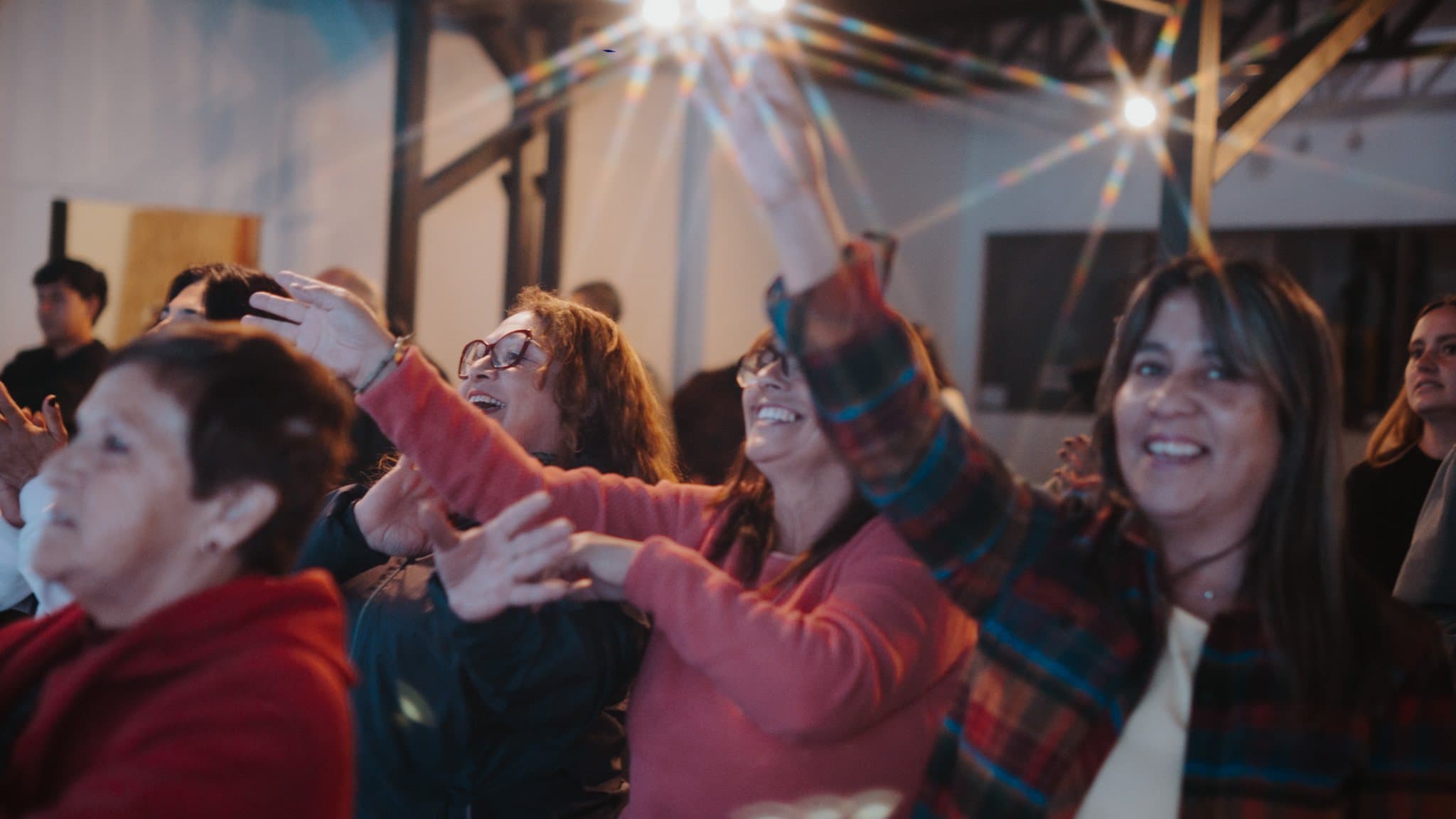 Mujeres de la congregación riendo y adorando en una reunión de la iglesia