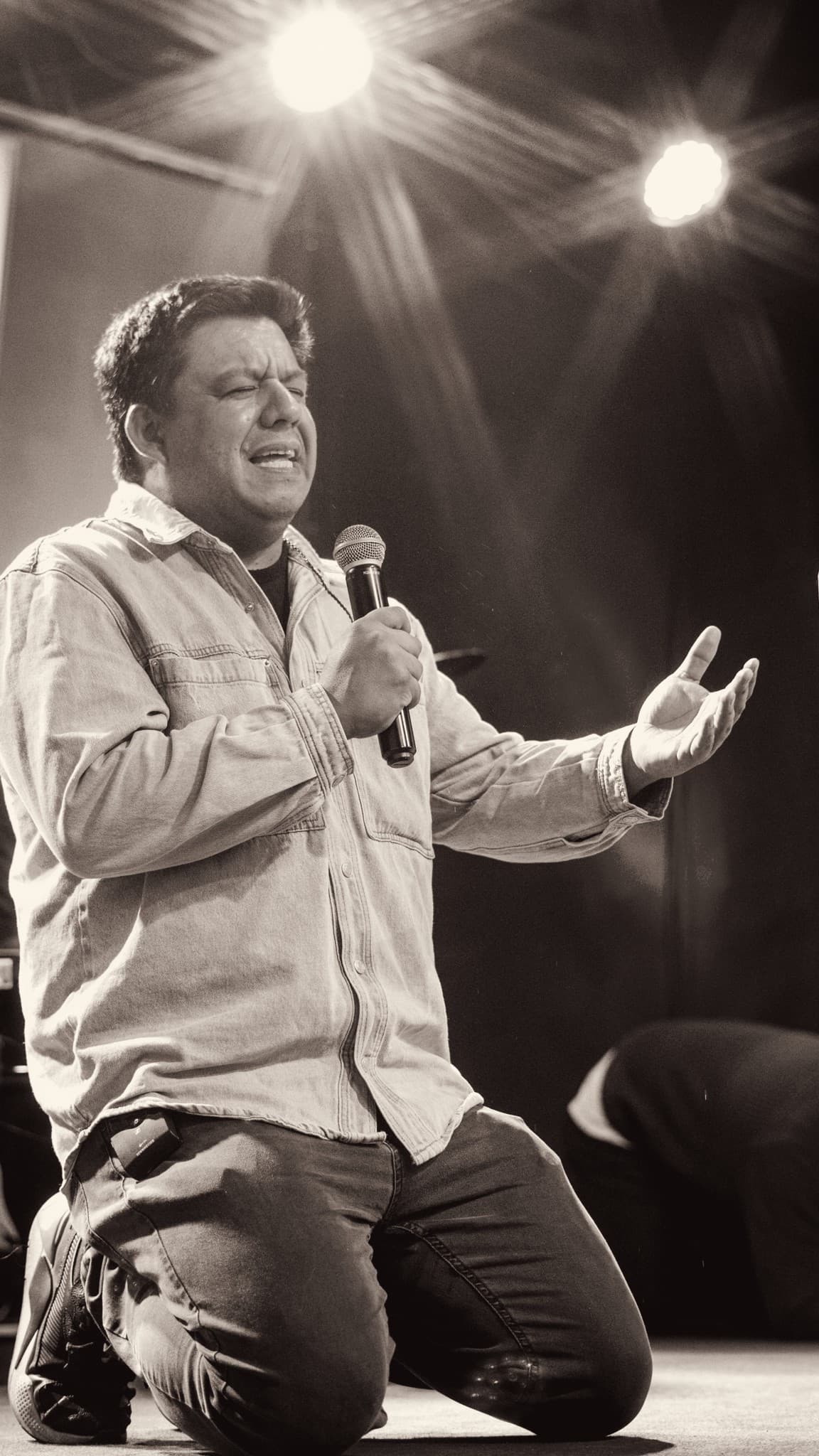 Un pastor ora de rodillas en el escenario