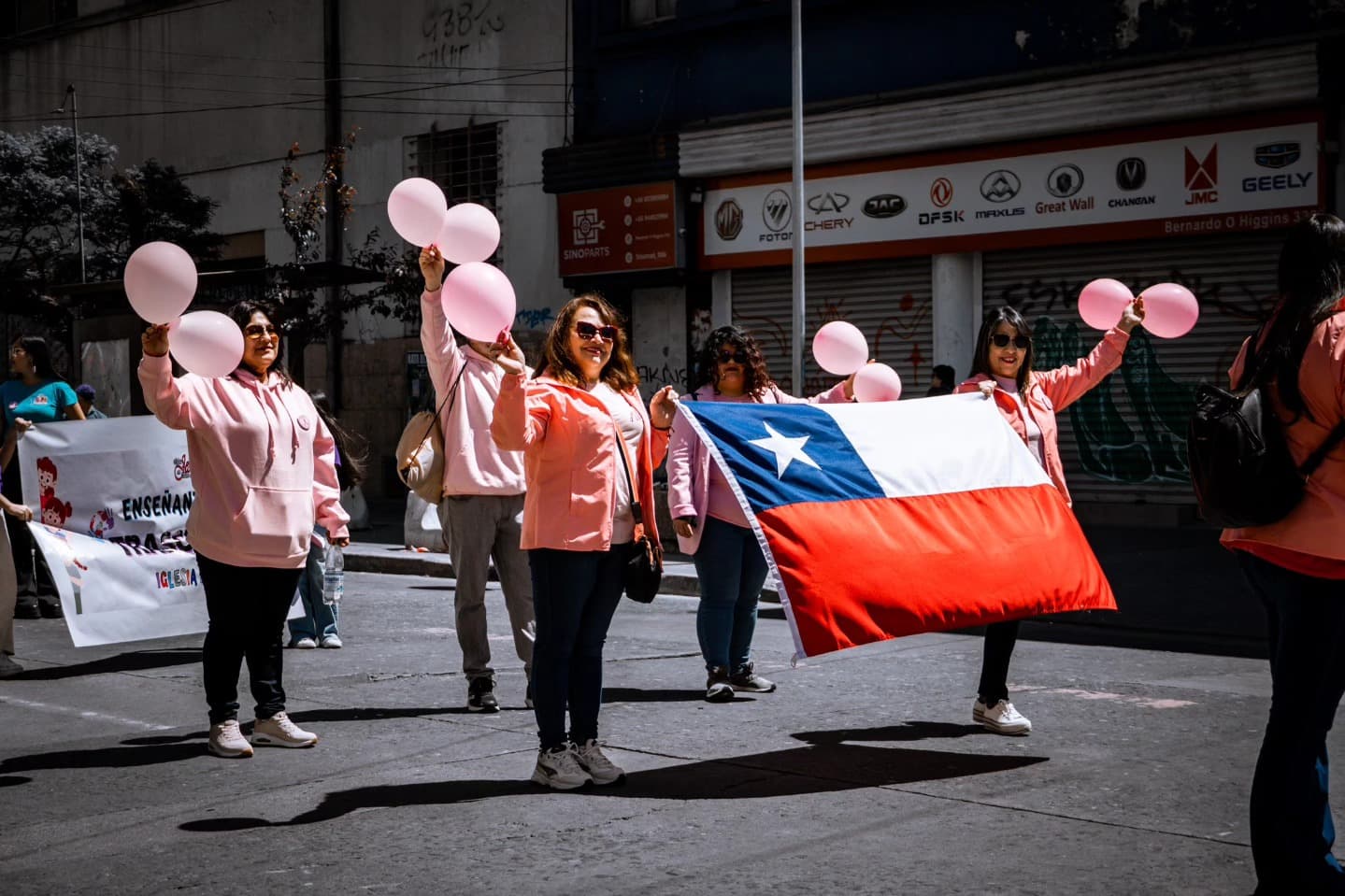 Voluntarias de Alma de Mujer con globos rosados y la bandera de Chile en un desfile